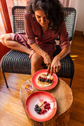 From above ethnic latin woman eating healthy breakfast almond flour pancakes with berries and honey - ADSF15848