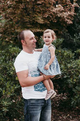 Father picking up daughter while standing in public park - EBBF00785