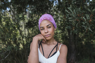 Confident young woman with purple bandana standing against plants at park - DSIF00145