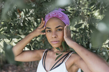 Confident young woman with purple bandana standing amidst plants at park - DSIF00149