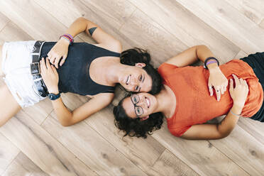 Lächelnde Freunde, die zu Hause auf dem Boden liegen - DGOF01504