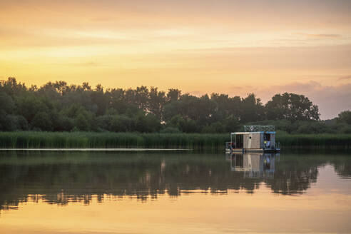 Reflection of houseboat in lake during sunset - MMAF01381