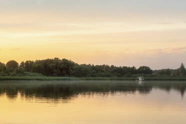 Distant view of houseboat in lake during sunset - MMAF01391