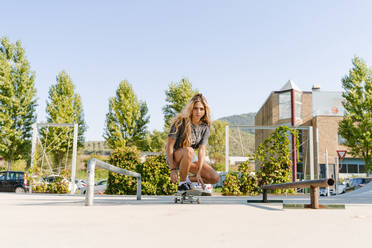 Selbstbewusste junge Frau auf dem Skateboard im Park gegen den klaren Himmel an einem sonnigen Tag - FMOF01176