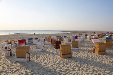 Hooded chairs at beach against sky during sunset - WIF04331