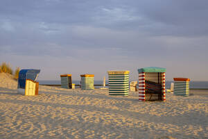 Gestreifte Zelte am Strand gegen bewölkten Himmel bei Sonnenuntergang - WIF04337