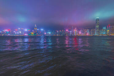 Illuminated buildings in city in front of sea against sky at night, Hong Kong - LCUF00117