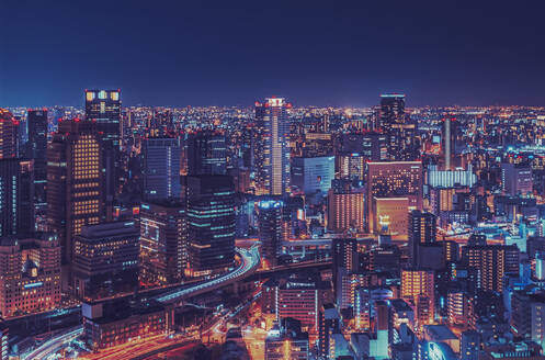 Illuminated modern buildings in city at night, Osaka - LCUF00118