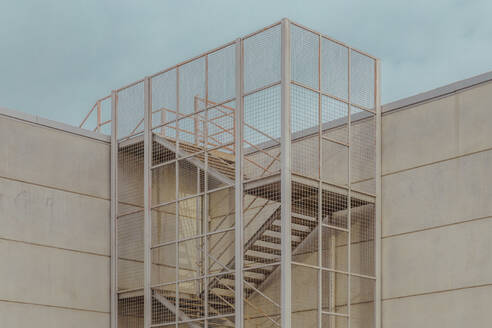 Metallic industrial ladder on wall against sky - LCUF00130