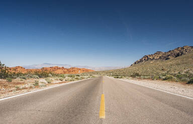 Schwindender Blick auf leere Wüstenstraße gegen blauen Himmel, Nevada, USA - DGOF01531