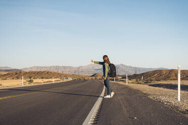 Woman hitchhiking on desert road, Nevada, USA - DGOF01542