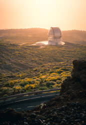 Hohe Winkel der atemberaubenden Landschaft mit Observatorium auf dem Hügel über den Wolken bei Sonnenuntergang - ADSF15903