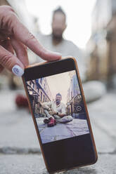 Frau fotografiert Mann mit Smartphone auf Gehweg in der Stadt - EYAF01345