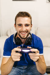 Smiling handsome young man playing video game at home - JRFF04752