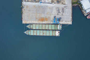 Drohnenansicht von Containerschiffen, die an einem Dock im Hafen auf dem blauen Meer vertäut sind - RSGF00308