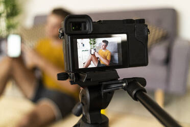 Personal trainer recording fitness in camera while sitting at home - GIOF08947