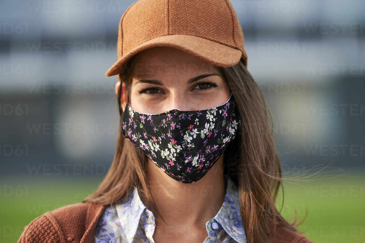 Young woman wearing cap and face mask standing in city stock photo