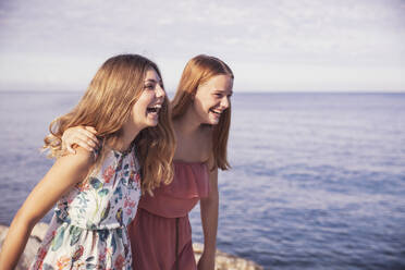 Friends laughing while standing on sidewalk during sunny day - DHEF00432