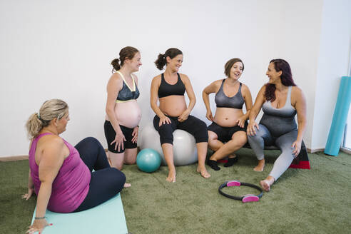 Eine Gruppe schwangerer Frauen lacht bei einer Übung im Yogastudio - MPPF01115
