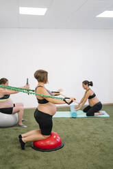 Schwangere Frau bei Übungen im Yogastudio - MPPF01118