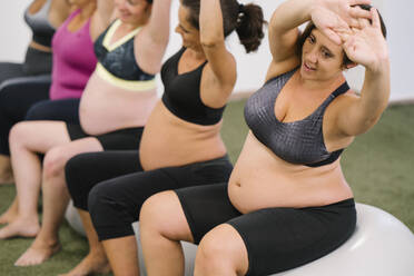 Midsection der schwangeren Frau tun Stretching-Übung beim Sitzen auf Fitness-Ball - MPPF01129