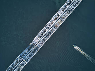 Directly above aerial view of boat moving over Volga River under metallic railway bridge - KNTF05530