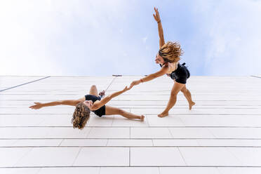 Aerial dancers holding hands and hand raised dancing on window - DLTSF01250