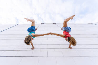 Aerial dancers upside down holding hands while hanging on window - DLTSF01252