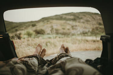 Tired mid adult couple lying in car trunk - DMGF00144