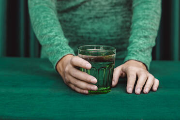 Midsection of woman holding glass of cocktail drink kept on table - ERRF04513