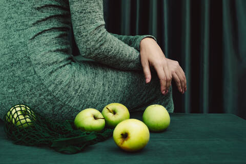 Midsection of female with green apple on table stock photo