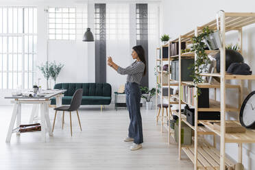 Weibliche Architektin nimmt Selfie von digitalen Tablet, während stehend gegen Rack im Büro - GIOF08973