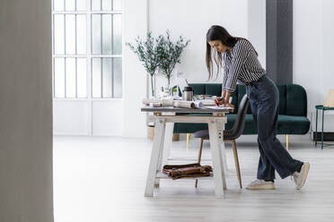 Junge Architektin stützt sich bei der Arbeit im Kreativbüro auf den Schreibtisch - GIOF08982