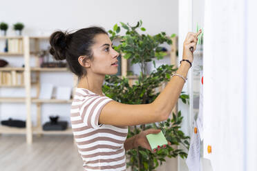 Junge weibliche Design-Profi berühren Whiteboard bei der Arbeit im Büro - GIOF08998