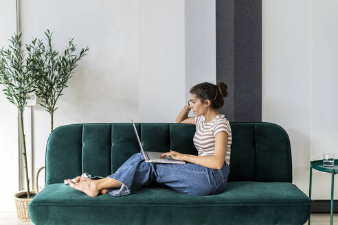 Selbstbewusste Designerin, die einen Laptop benutzt, während sie auf dem Sofa im Kreativbüro sitzt - GIOF09013