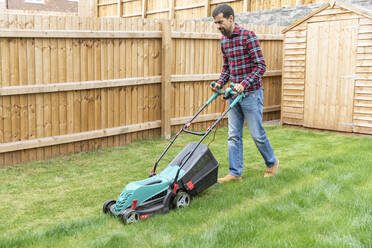Mi
d adult man cutting grass with lawn mower at backyard - WPEF03417