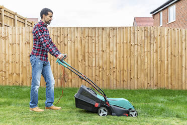 Man mowing with lawn mover at backyard - WPEF03425