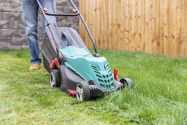 Mid adult man standing with lawn mower at backyard - WPEF03426