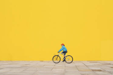 Behinderter Mann fährt mit dem Fahrrad gegen eine gelbe Wand - JCZF00257