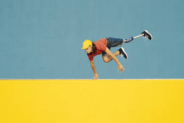 Mann mit körperlicher Behinderung springt gegen mehrfarbige Wand - JCZF00282