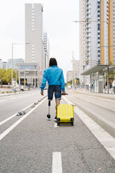 Junger Mann geht mit Gepäck auf der Straße in der Stadt - JCZF00295