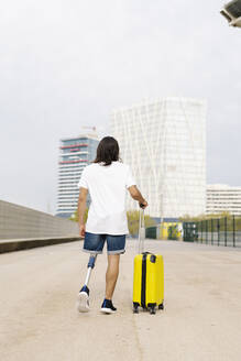 Behinderter Mann geht mit Gepäck auf dem Bürgersteig in der Stadt - JCZF00311