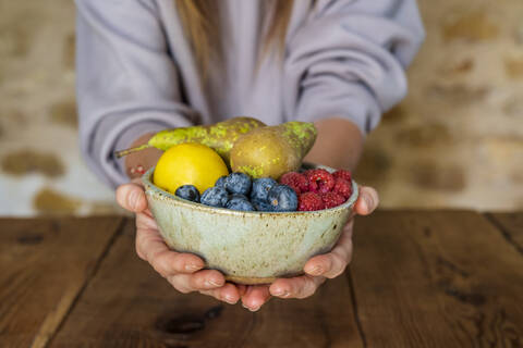 Close-up of various fruits in bowl held by female nutritionist at table stock photo