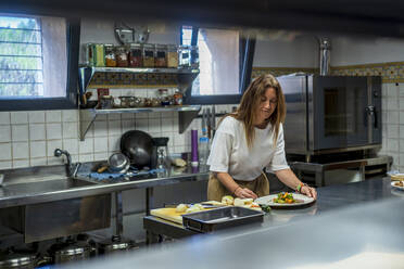 Confident female dietitian preparing meal at commercial kitchen - DLTSF01280