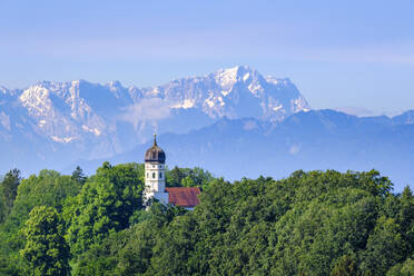 Deutschland, Bayern, Holzhausen, St. Johann Baptist Kirche umgeben von grünem Wald im Sommer mit Zugspitze in der Ferne Hintergrund - SIEF10051