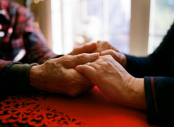 Father holding daughter's aged hands. Comforting warming old age - CAVF89733