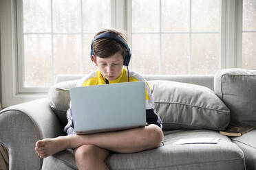 Preteen Boy Wearing Headphones Works on Laptop for Virtual School - CAVF89736