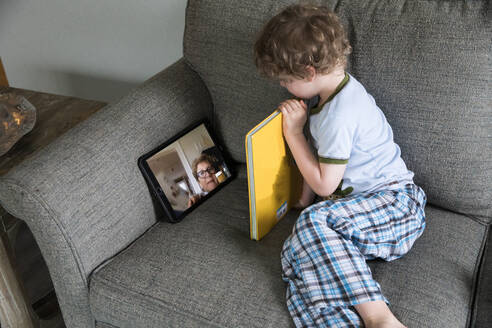 Preschool Boy Reads Book With Grandma Over Video Chat - CAVF89739