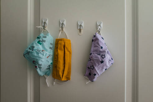 Three cloth masks hanging on hooks in closet - CAVF89753
