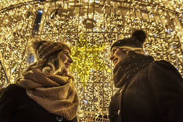 Two young girls are laughing in the background of Christmas lights - CAVF89761